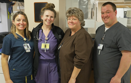 A photograph of four nurses standing together looking at the camera