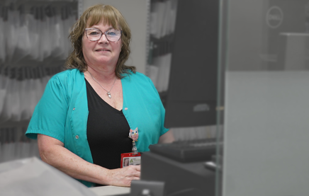 Photograph of a smiling pharmacy technician at the counter.